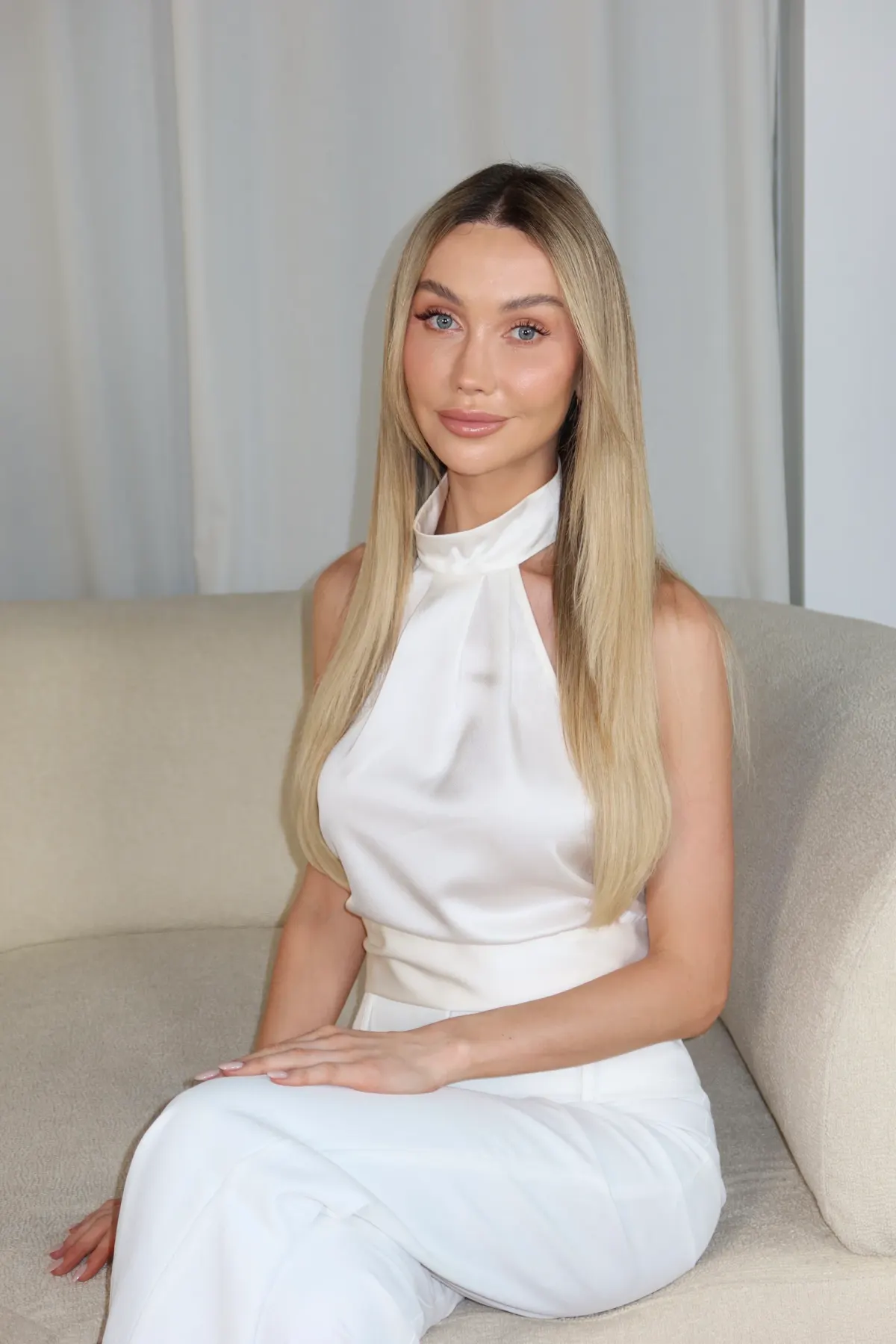 Abby sitting on an ivory sofa, smiling gently to camera.